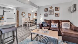 A modern living room with a brown leather sofa, a coffee table, and a dining area with a wooden table and chairs. - FANTASTIC 2 BR 2 Blocks to beach pool balcony (Seaside Heights)