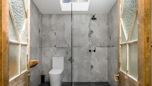 A modern bathroom with a skylight, a toilet, and a shower. - Byron Bay hinterlands vintage-styled nature oasis! (Myocum)