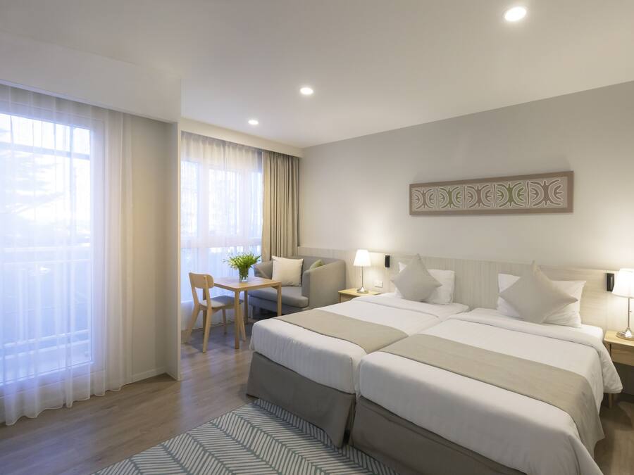A hotel room with two beds, a desk, and a chair.
