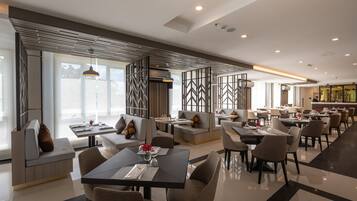 A modern dining area with high tables, comfortable seating, and a view of the outdoors.