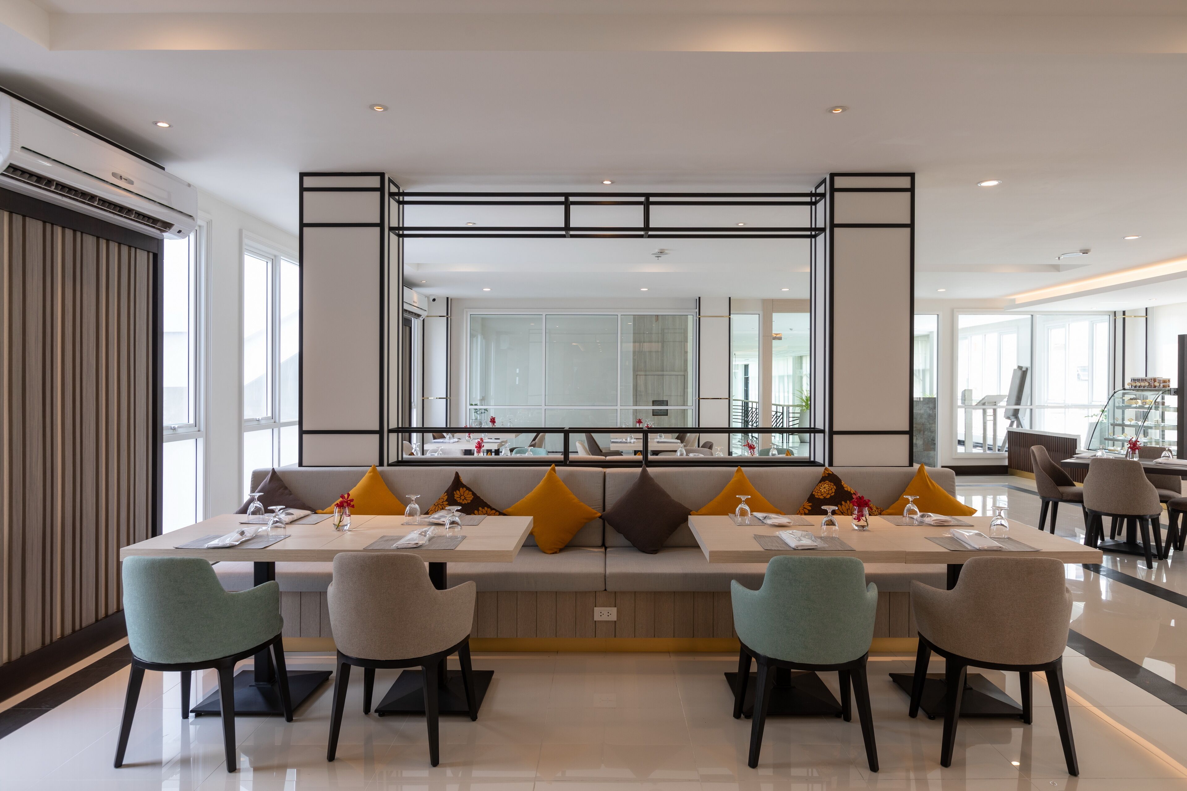 A modern dining area with a long table, multiple chairs, and a large mirror above.