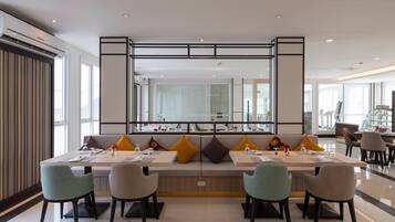 A modern dining area with a long table, multiple chairs, and a large mirror above.