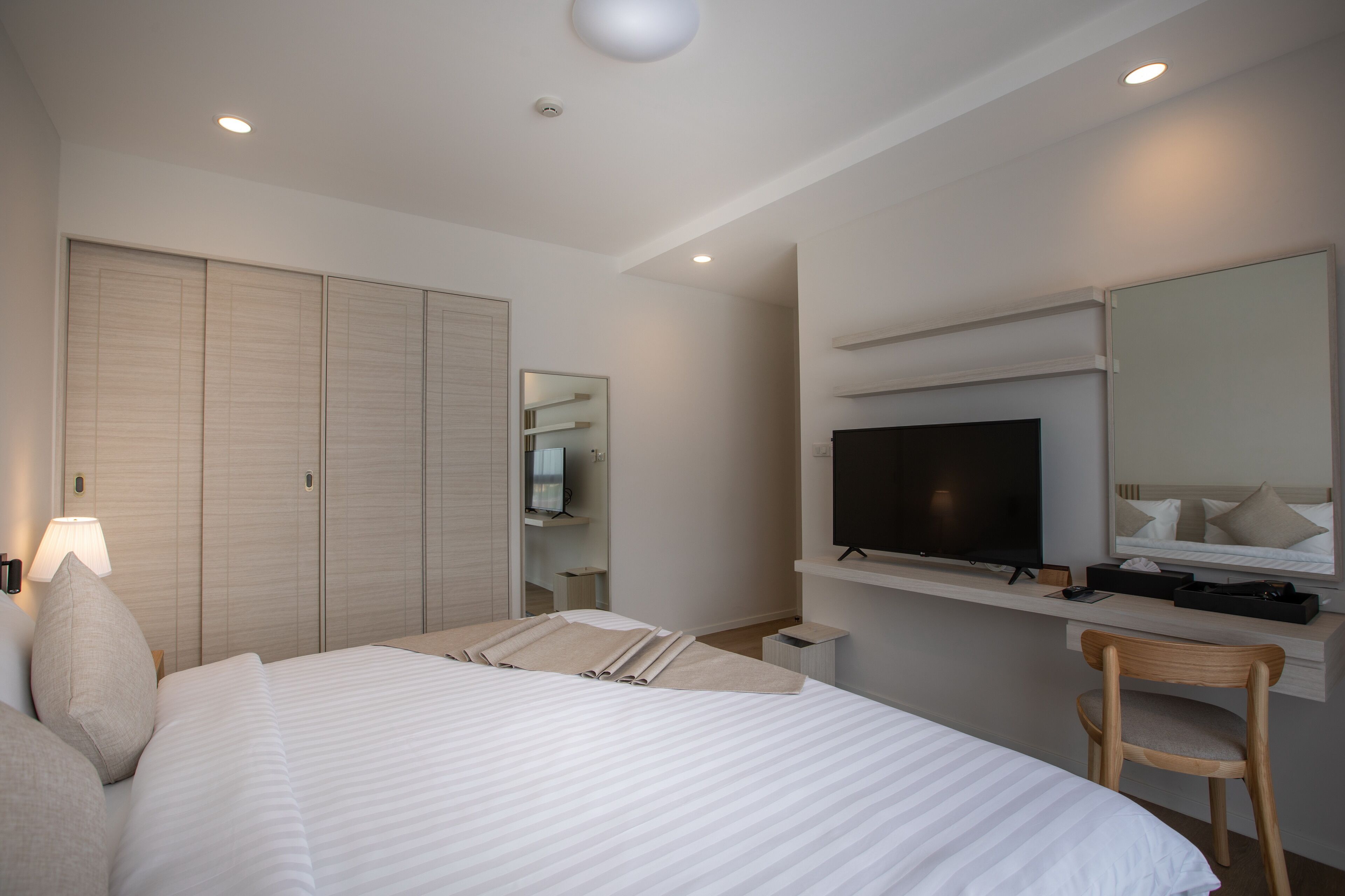 Een hotelkamer met een groot bed, een bureau met een televisie, een stoel en een kledingkast.