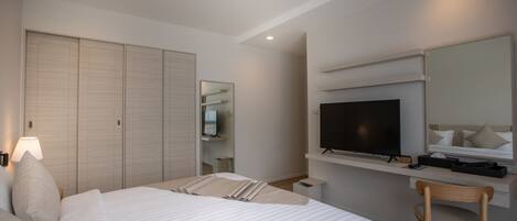 Habitación de hotel con una cama grande, un escritorio con televisor, una silla y un armario.