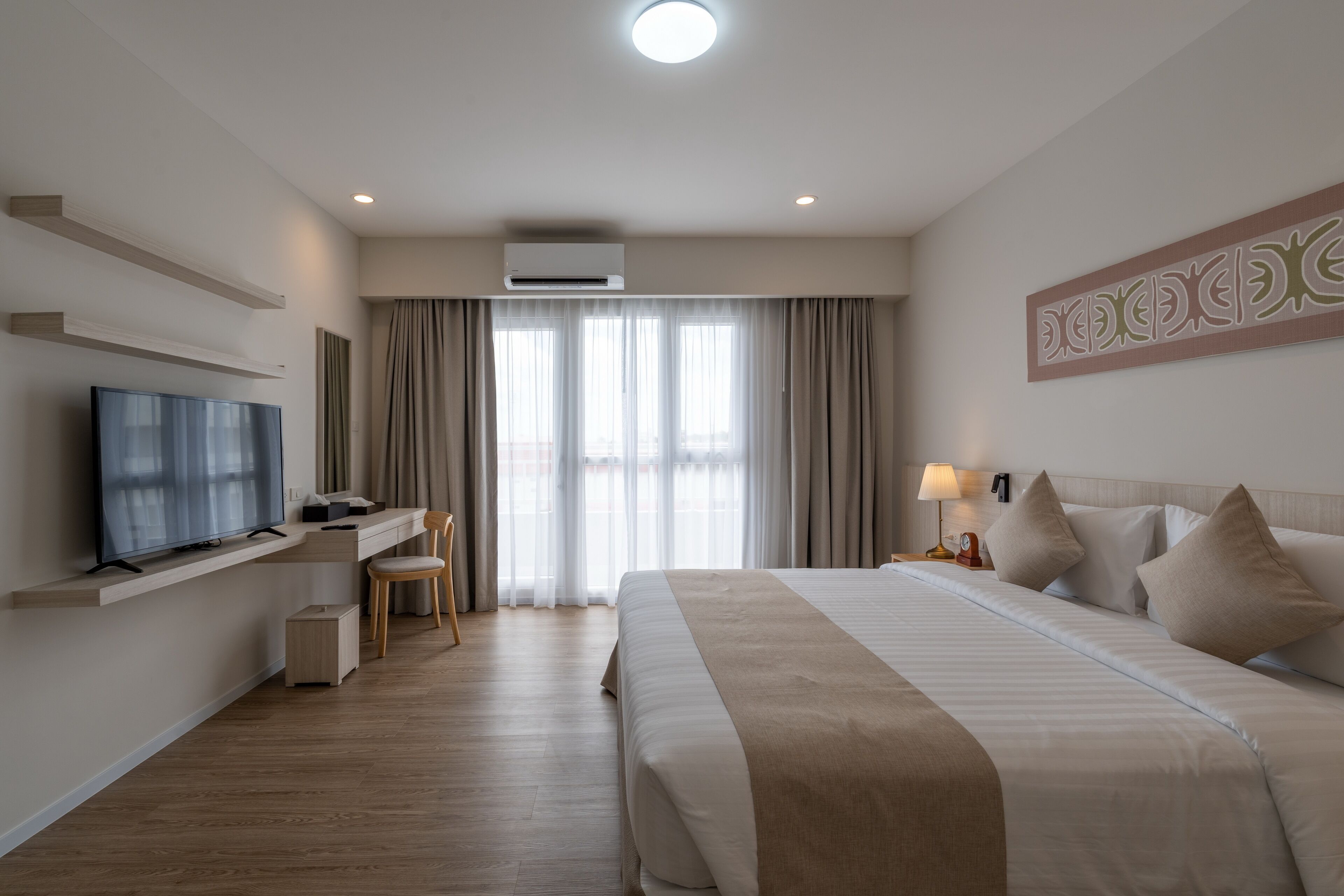 A hotel room with a bed, a TV, a desk, and a chair.