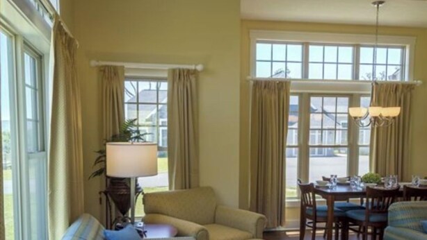 A living room with a sofa, armchair, and dining table. - Luxury Resort in Shenandoah Valley (McGaheysville)