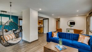 Een moderne woonkamer met een blauwe bank, een hangstoel en een houten salontafel.