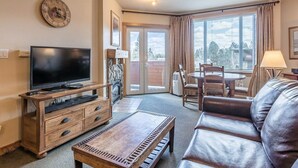 Un soggiorno con televisione, mobile TV in legno, divano in pelle e zona pranzo con tavolo e sedie.