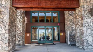 L'ingresso di un edificio con facciata in pietra, ampie porte in vetro e una tettoia in legno.