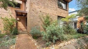 Une maison moderne en briques, avec un chemin en béton menant à l’entrée.