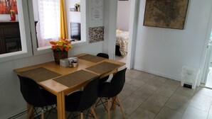 A dining area with a wooden table, black chairs, a vase of flowers, and a television on the wall. - Vibrant apartment in the heart of the town (Edmundston)