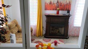 A room with a dining table, a fireplace, and a view through a window. - Vibrant apartment in the heart of the town (Edmundston)
