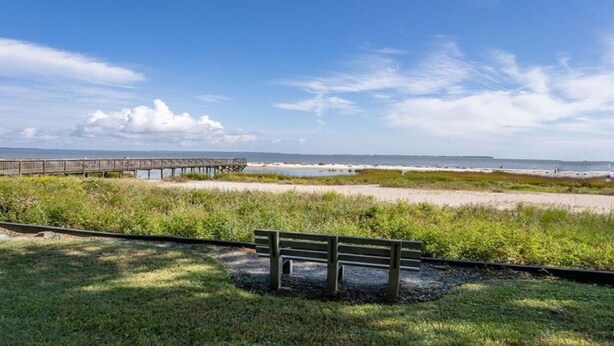 A wooden bench in a grassy area with a wooden pier extending into the water. - Blissful Villa, King Bed (Hilton Head Island)
