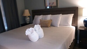 A neatly made bed with white linens and a brown pillow with a quote. - Blissful Villa, King Bed (Hilton Head Island)