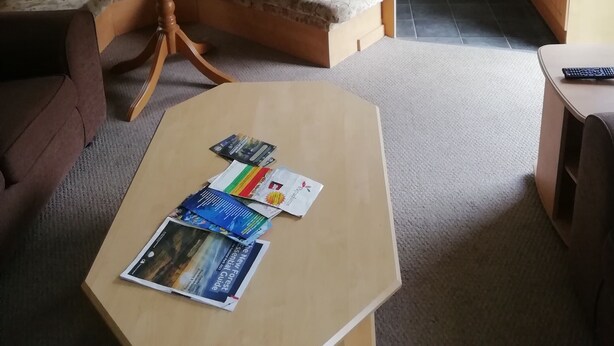 Een knus leefruimte met een bank, een klein rond tafeltje met tijdschriften, een kitchenette met een magnetron en een vaatwasser.