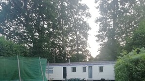 Een gazon met een stacaravan op de achtergrond.