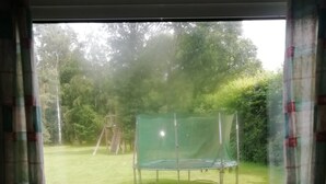 Een keuken met een raam dat uitkijkt op een gazon met een trampoline en stoelen.