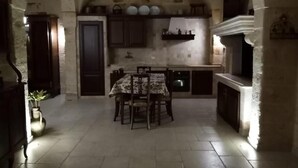 A rustic kitchen with stone walls, a tiled floor, a dining table with chairs, and a built-in oven. - Holiday Home" C'era una Volta" (Torricella)