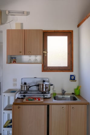 A compact kitchen with wooden cabinets, a gas stove, a sink, and a window above the sink. - House With With a Spectacular sea View (Samos)