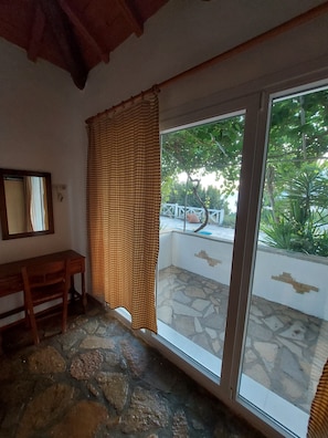 A room with a stone floor, a wooden desk, a window with a view of greenery, and a white wall. - Astonishing House With sea View in Samos Island (Samos)