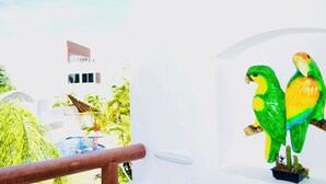 Un edificio blanco de diseño moderno, con una piscina y dos esculturas de loros.
