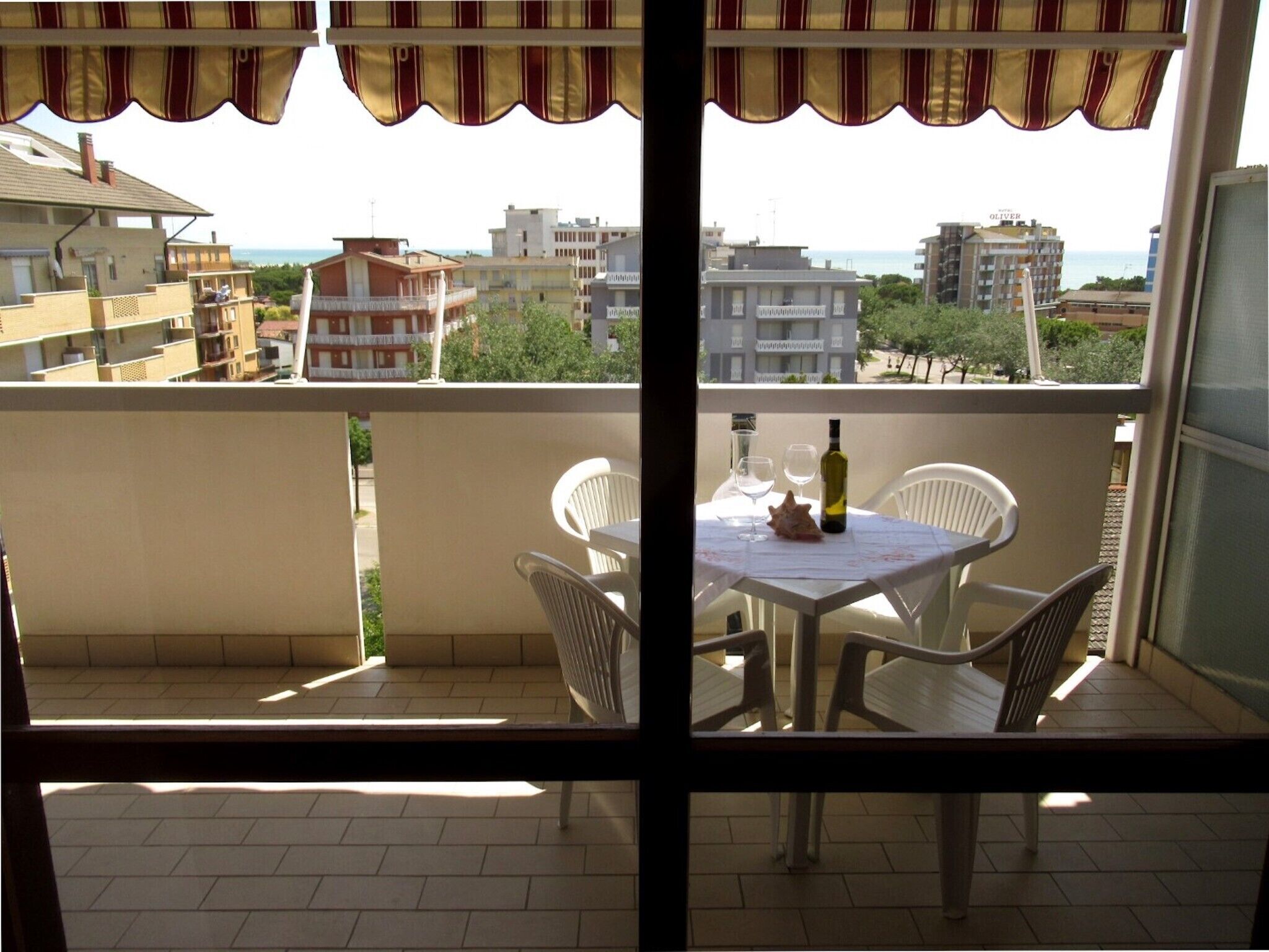 A balcony with a table, chairs, a bottle, and glasses.