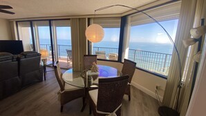 Ein geräumiger Balkon mit Meerblick, ausgestattet mit Korbstühlen und einem Glastisch.