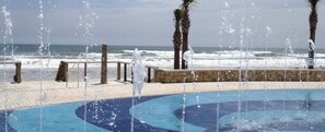 Ein Pool mit Wasserstrahlmassagen, Palmen und Blick auf den Ozean.