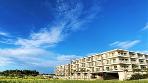 Un hôtel à plusieurs étages doté de balcons, d’un parking et offrant une vue sur un paysage verdoyant.