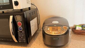 A kitchen with a microwave and a rice cooker.