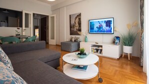 Una sala de estar moderna con un sofá, una mesa de centro, un televisor y una estantería.