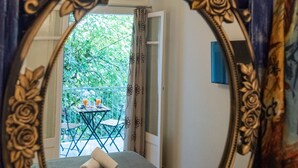 Una habitación con un espejo grande y ornamentado que refleja un balcón exterior con una mesa y sillas.