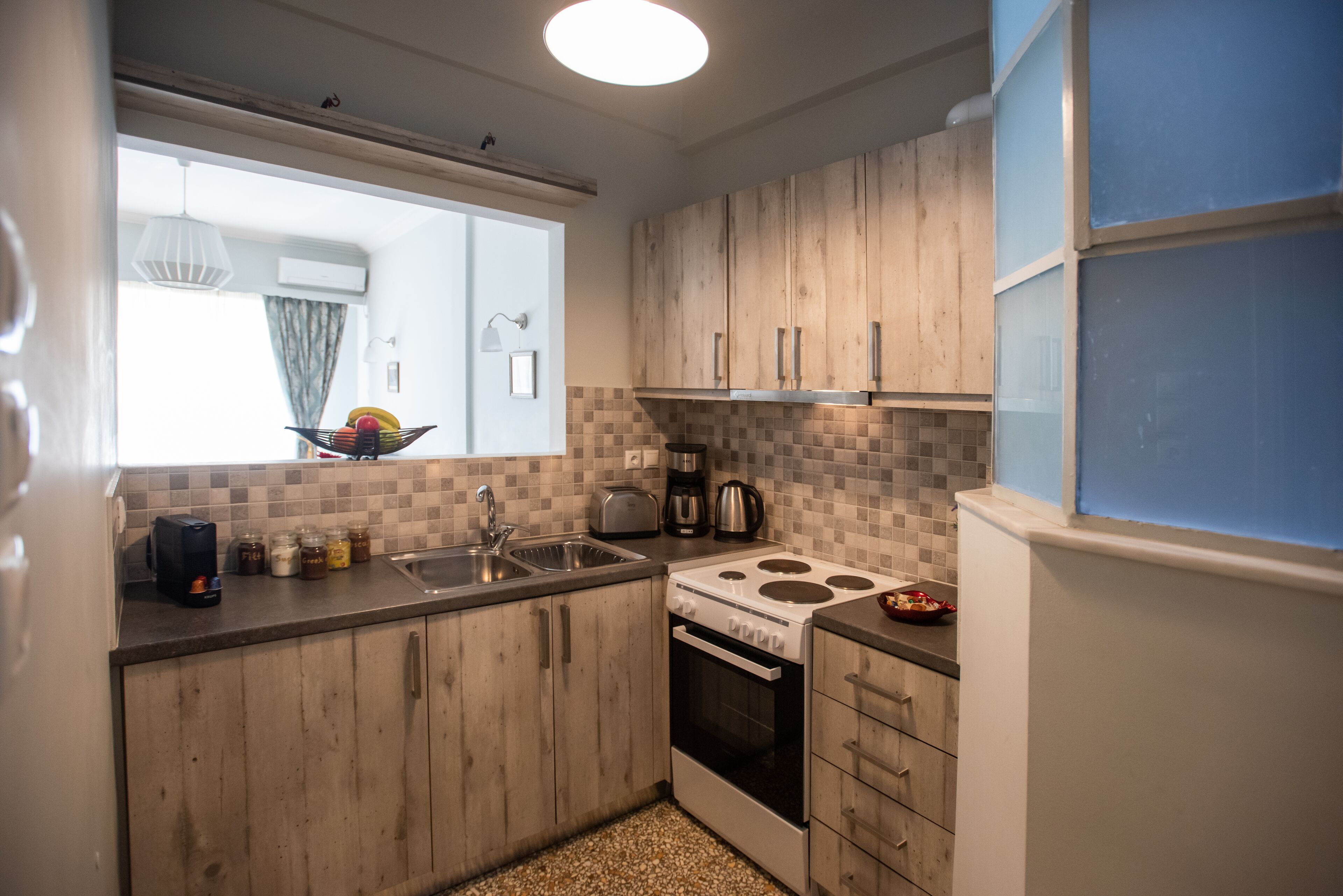 A compact kitchen with wooden cabinets, a gas stove, a sink, and a window with a view of the outdoors.