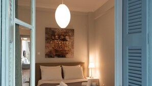 Un dormitorio con una cama, una lámpara colgante y un cuadro en la pared.