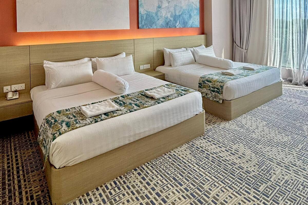 Habitación de hotel con dos camas, alfombra estampada y arte abstracto en la pared.