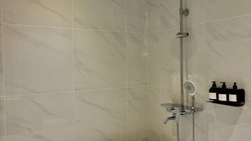 A modern bathroom with a freestanding bathtub, a walk-in shower with a handheld showerhead, and a wall-mounted soap dispenser.