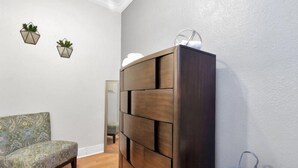 A room with a dark wooden dresser, a patterned armchair, and two wall-mounted planters. - Downtown Studio by Toyota Center/Minute Maid/ George R Brown (Houston)
