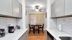 A kitchen with white cabinets, a wooden floor, a dining table with chairs, and a ceiling fan. - Downtown Studio by Toyota Center/Minute Maid/ George R Brown (Houston)