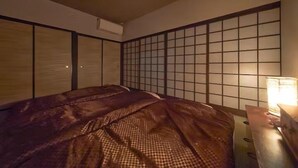 Una habitación con una cama, cabecera de madera, pared con diseño de cuadrícula y mesita de noche con lámpara.