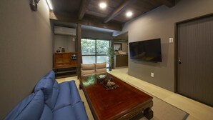 Una sala de estar con un sofá, una mesa de centro, un televisor y un ventanal corredera.
