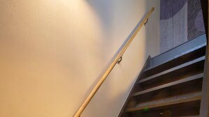 Una escalera de madera con barandilla que conduce a un rellano con pared de mármol.