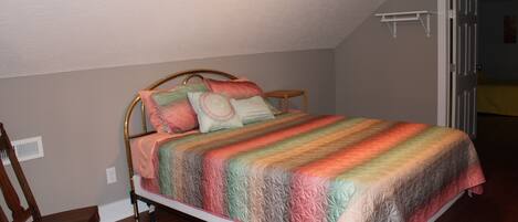 A bedroom with a bed, a wooden chair, and a door leading to another room.