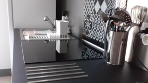 Een moderne keuken met een zwart aanrecht, roestvrijstalen apparatuur en een betegelde achterwand.