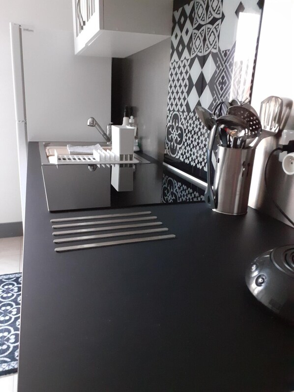 A modern kitchen with a black countertop, stainless steel appliances, and patterned backsplash.