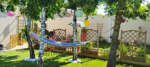 Un jardin agrémenté d’un hamac, de portails en treillis de bois et de plantes en pot.