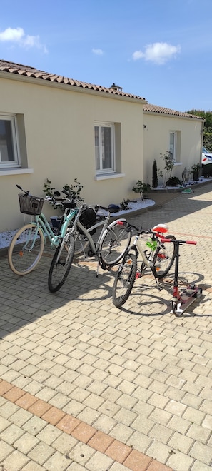 A paved driveway with bicycles parked in front of a building with a tiled roof and windows.