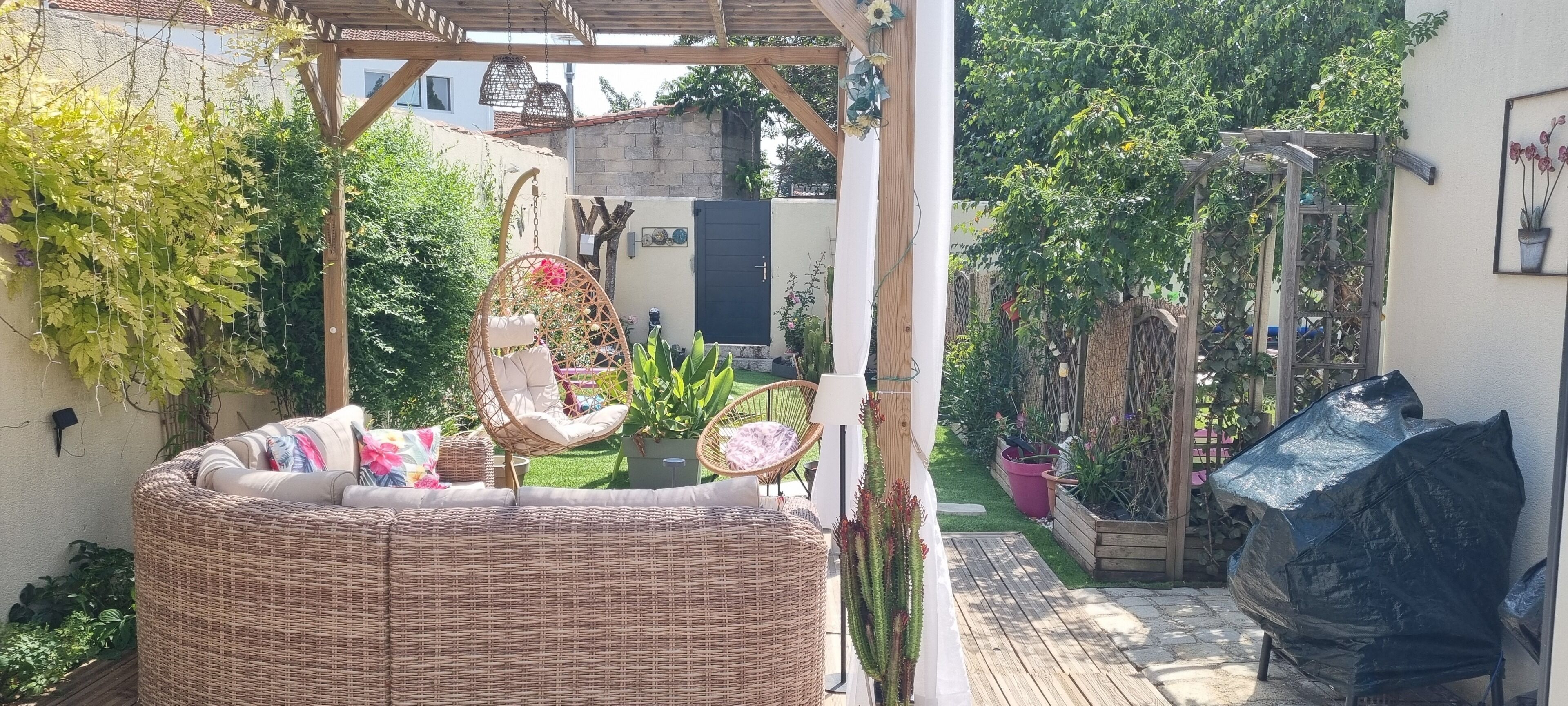 A covered outdoor seating area with wicker furniture and a hanging chair.