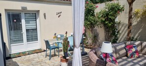 Une terrasse avec une table et des chaises, un canapé, une lampe et une plante en pot.