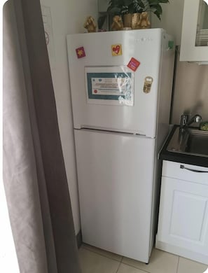 A compact kitchen with a white refrigerator, a sink, and cabinets.