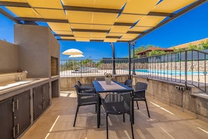 An outdoor patio with a table and chairs, a grill, and a view of a swimming pool. - Charming holiday house LUCIJA (Žgaljići)